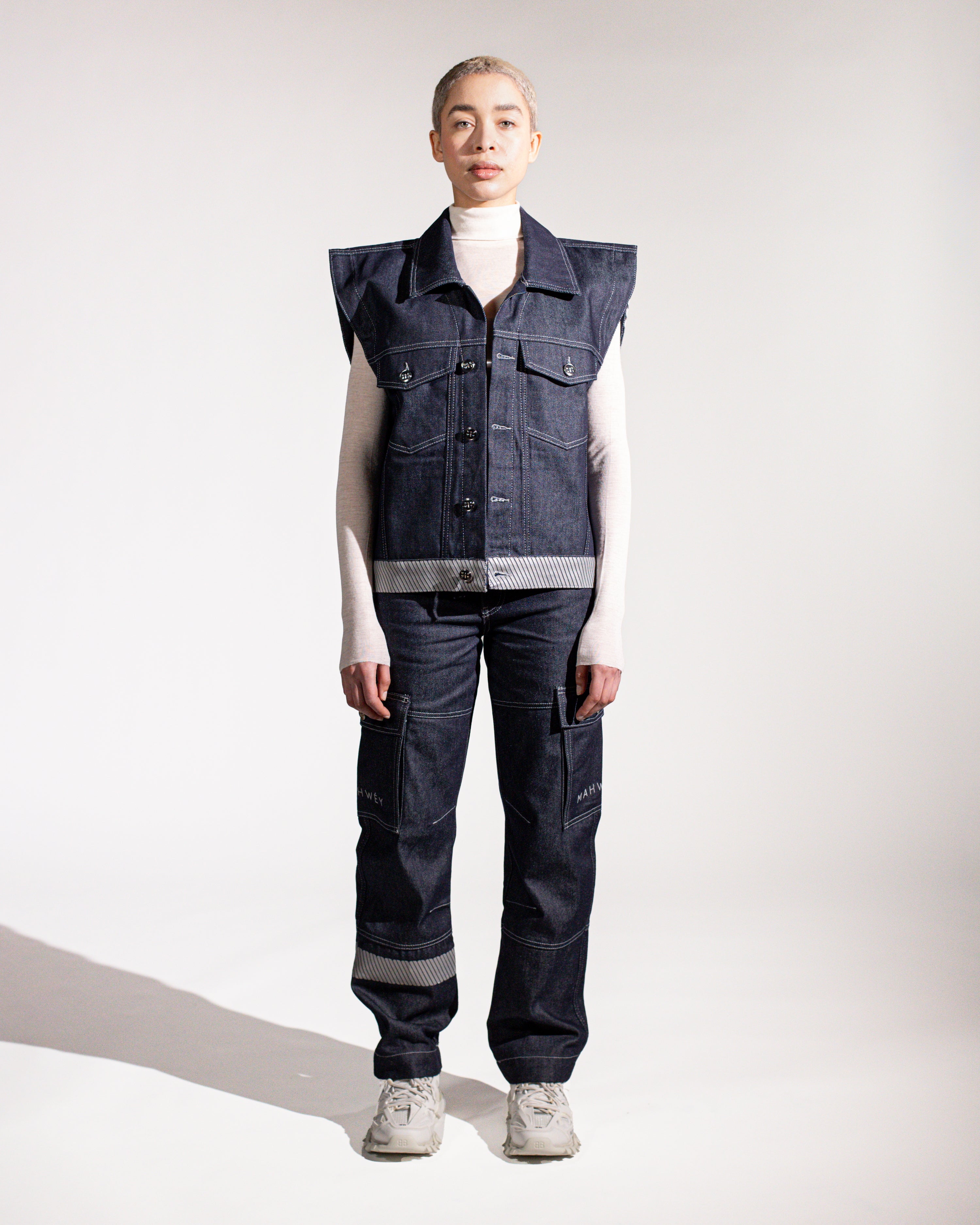 A model wearing an oversized denim gilet with a square shoulder design, paired with matching denim jeans.